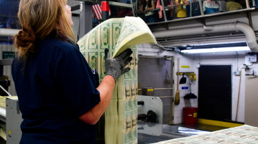 US mint worker holding sheets of $20 bills � AFP via Getty Images